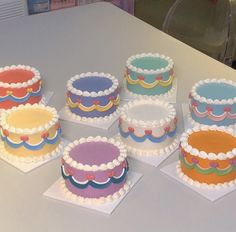 six cakes are arranged on top of each other in different colors and designs, with white frosting around the edges