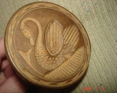 a carved wooden button with a bird in the center and leaves on it's side