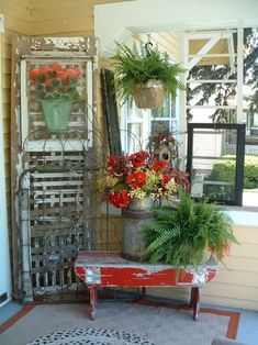 a red bench sitting in front of a window filled with potted plants and flowers