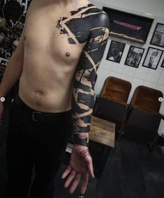 a man with his arm covered in black and white ink, standing in front of a table