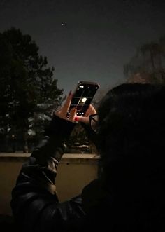 a person holding up a cell phone to take a photo with the moon in the background