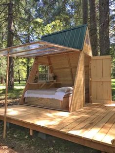 a bed in the middle of a wooden platform with a green roof and windows on it