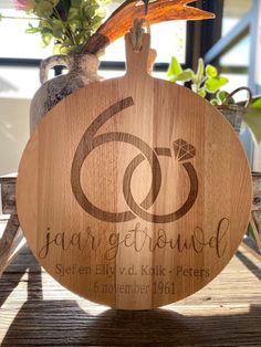 a wooden cutting board sitting on top of a table next to a potted plant