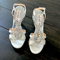 a pair of white wedding shoes on top of a wooden floor