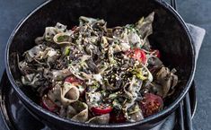 a black bowl filled with pasta and vegetables