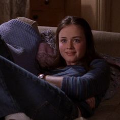 a woman laying on top of a couch with her legs crossed and looking at the camera