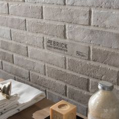 a brick wall next to a wooden table with two soap dispensers on it