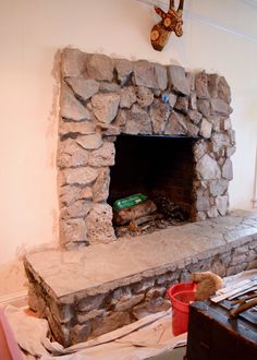 a stone fireplace in the middle of a room with construction materials on the floor around it