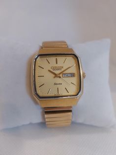 Presenting a vintage Citizen Seven Quartz watch, known for its reliable performance and classic design. This timepiece features a gold-tone case and bracelet, which adds a touch of elegance to its overall appearance. The champagne dial is complemented by gold-tone markers and hands, creating a timeless look that can easily transition from casual to formal settings. The watch is powered by a quartz movement, ensuring accurate timekeeping. The day-date function at the 3 o'clock position adds pract Antique Yellow Gold Self-winding Watch, Citizen Watch, 3 O Clock, Champagne Color, O Clock, Wrist Watches, Quartz Watch, Stretch Bracelet, Quartz Movement