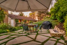 a patio with an umbrella over it and some chairs around the table in the yard