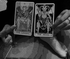 two tarot cards being held in front of each other by someone's hands