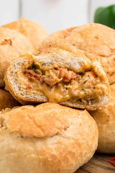 a pile of bread rolls sitting on top of a wooden cutting board next to peppers