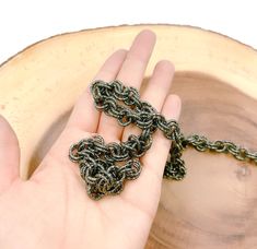 a hand holding a chain on top of a wooden bowl