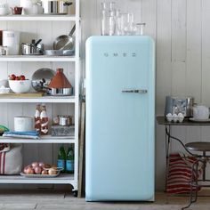 an old fashioned blue refrigerator with a pineapple painted on the front and bottom, in a kitchen