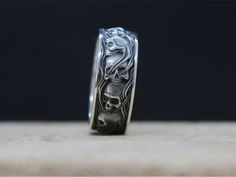 a silver ring with a skull and crossbones on the side, sitting on a wooden surface