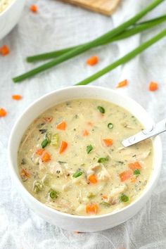 a bowl of soup with carrots, celery and peas on the side