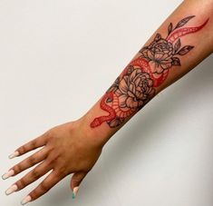 a woman's arm with a rose and snake tattoo on it