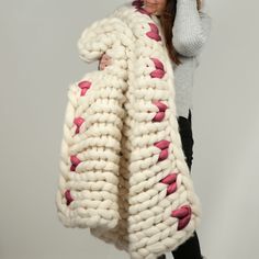 a woman wearing a white and pink knitted coat