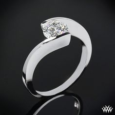 a white gold ring with a single diamond in the center on a black background,