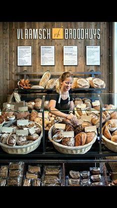 a woman standing in front of a display case filled with bread