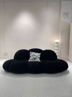 a large black couch sitting on top of a white floor next to a wall mounted light