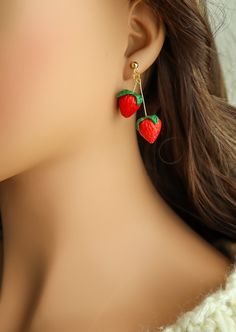 a close up of a person wearing earrings with strawberries on them