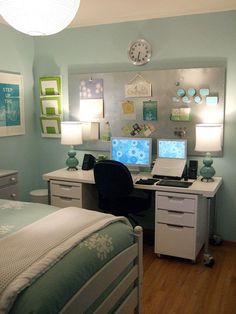 a bed room with a neatly made bed and two computer desks