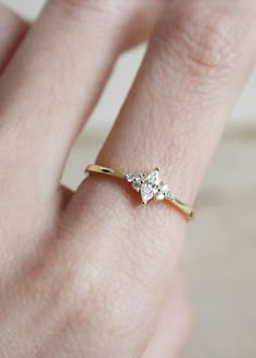 a woman's hand with a diamond ring on top of her finger, showing the side view