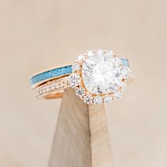 a close up of a ring on top of a wooden stand with a diamond and blue band