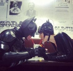 two people dressed as batman and catwoman sitting at a table