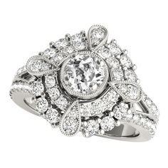 a white gold ring with an oval cut diamond surrounded by smaller round diamonds