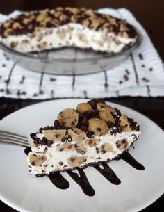 a slice of ice cream pie on a white plate with chocolate chips and nuts drizzled over it