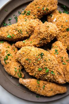 some fried chicken is on a plate with parsley sprinkled around it's edges