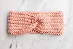 a pink knitted headband on a marble surface