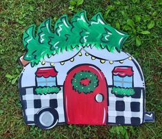 a cardboard house with a christmas wreath on the front door and green grass around it