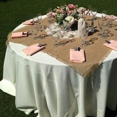 the table is set with pink napkins, silverware and wine glasses on it