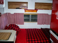 a red and black checkered bedspread in a small room with coca - cola signs on the window