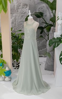 a dress is displayed on a mannequin in front of a wall with plants