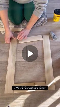 a woman is making a wooden frame for a wall hanging on the floor with wood glue