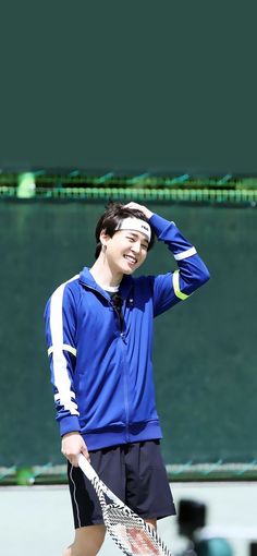 a young man holding a tennis racquet on top of a tennis court