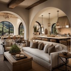 a living room filled with furniture next to an open kitchen and dining area in the background