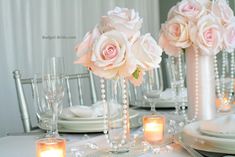 the table is set with white and pink flowers, candles, and crystal vases