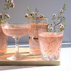 three glasses with flowers in them sitting on a table