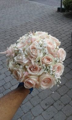 a person holding a bridal bouquet in their hand on a brick sidewalk next to a bike