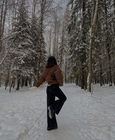 a woman in brown jacket standing on snow covered ground