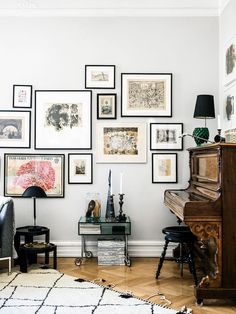 a living room filled with lots of framed pictures on the wall next to a piano