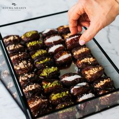 a person is picking up some food from a glass tray on a marble countertop