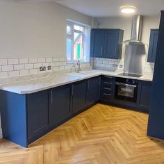 an empty kitchen with wooden floors and blue cabinets