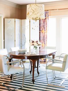 a dining room table with white chairs and a chandelier