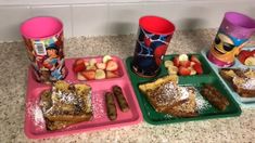 three trays filled with different types of food on top of a counter next to cups